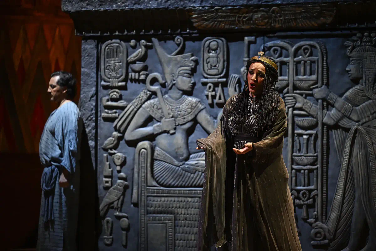Escena de Aída con una intérprete ante un gran relieve inspirado en el antiguo Egipto.