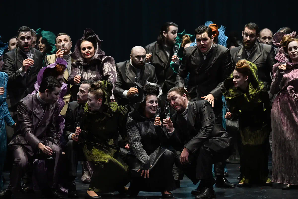 Escena de Hamlet con un grupo de intérpretes reunidos en primer plano sobre el escenario.
