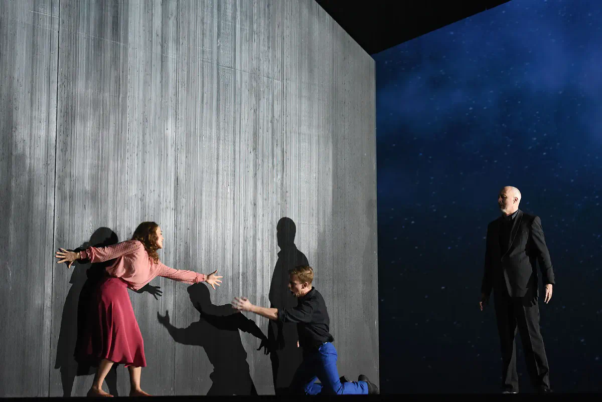 Escena de Pelléas et Mélisande con dos personajes separados por una gran pared gris.