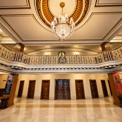 Vestíbulo principal del Teatro Campoamor de Oviedo con galería superior y lámpara de cristal.